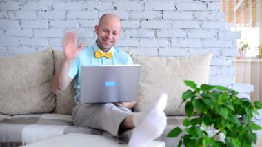 Aşk kilit altında. Gömlekli ve papyonlu bir adam selamlaşmak için elini sallıyor ve sanal randevuda sevgilisine bir öpücük yolluyor. Sevgililer Günü 'nde görüntülü sohbetteki mutlu adam kendini izole ediyor..