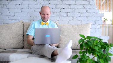 Sanal tatil. Online randevuda tişörtlü ve papyonlu şık erkek blogcu. Mutlu insan mutlu bir şekilde konuşur, güler ve güler bir görüntülü sohbet sırasında kendini izole eder. Yalnızken aşk.