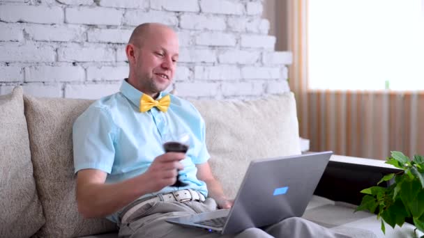 Vacaciones virtuales. Elegante hombre de camisa y pajarita con copa de vino en la cita en línea a través de llamada. Feliz hombre dice tostadas y celebra remotamente las vacaciones en el chat de vídeo en auto-aislamiento. Amor en encierro. — Vídeo de stock