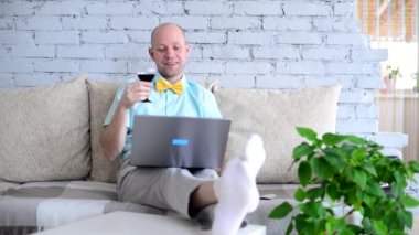 Sanal tatil. Online randevuda, tişörtlü ve papyonlu şık bir adam ve bir bardak şarap. Mutlu adam tost diyor ve tatilini uzaktan izole bir şekilde görüntülü sohbet ederek kutluyor. Kilit altında aşk.