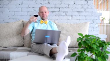Sanal tatil. Online randevuda, tişörtlü ve papyonlu şık bir adam ve bir bardak şarap. Mutlu adam tost diyor ve tatilini uzaktan izole bir şekilde görüntülü sohbet ederek kutluyor. Kilit altında aşk.