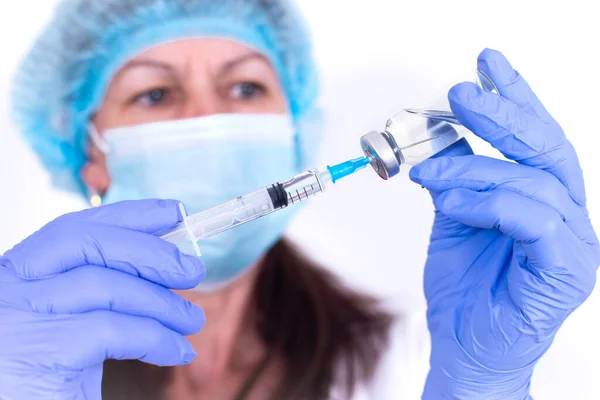 Vrouwelijke arts met beschermend masker en handschoenen typt het vaccin in de spuit. Een close-up. viroloog wetenschapper. Preventie tegen influenza, viruspandemie, coronavirus. Verplichte vaccinatie van mensen. — Stockfoto