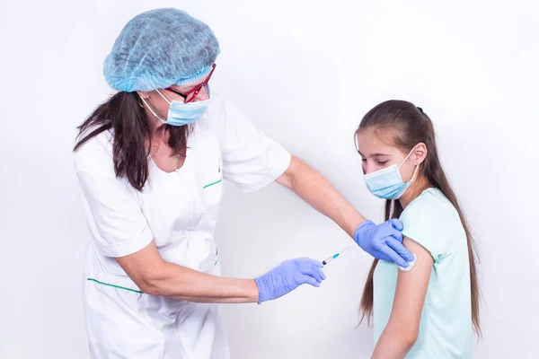 女性小児科医や看護師は、肩の患者にショットやワクチンを与える-若い女の子.インフルエンザ、パンデミックコロナウイルスに対するワクチン。ウイルスからの免疫のための人々の必須予防. ロイヤリティフリーのストック写真