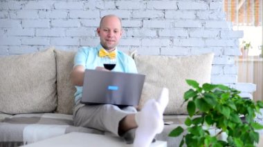 Sanal tatil. Online randevuda, tişörtlü ve papyonlu şık bir adam ve bir bardak şarap. Mutlu adam tost diyor ve tatilini uzaktan izole bir şekilde görüntülü sohbet ederek kutluyor. Kilit altında aşk.