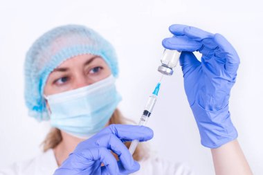 Koruyucu maskeli ve eldivenli kadın doktor şırıngaya aşı yazıyor. Yakın plan. Virolog bilim adamı. Gribe karşı önlem, virüs salgını, koronavirüs. İnsanların zorunlu aşılanması.