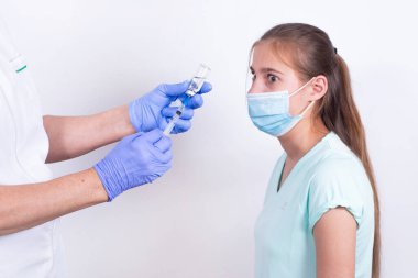 Çocuk iğneyi yapmaya korkuyor. Pediatrik doktor ya da hemşire hastaya aşı ya da iğne yapar. Genç kız. Grip aşısı, pandemik koronavirüs. Zorunlu önleme.