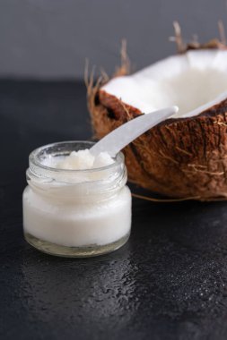 Cam bir kavanozda açık hindistan cevizi ve kozmetik yağı zıt bir arkaplanda yakın plan..