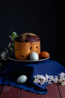 Çikolata kremalı ve tavuk yumurtalı Paskalya pastası ve arka planda çiçek açan kiraz dalı. Neşeli natürmort