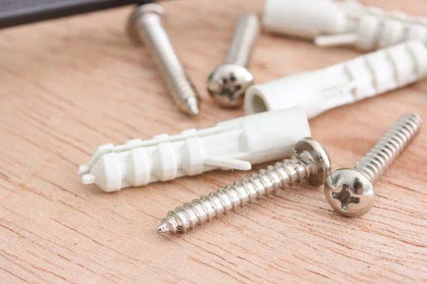 Screws and plastic anchor on the wooden background — Stock Photo, Image