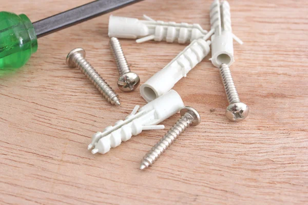 Screws and plastic anchor on the wooden background — Stock Photo, Image