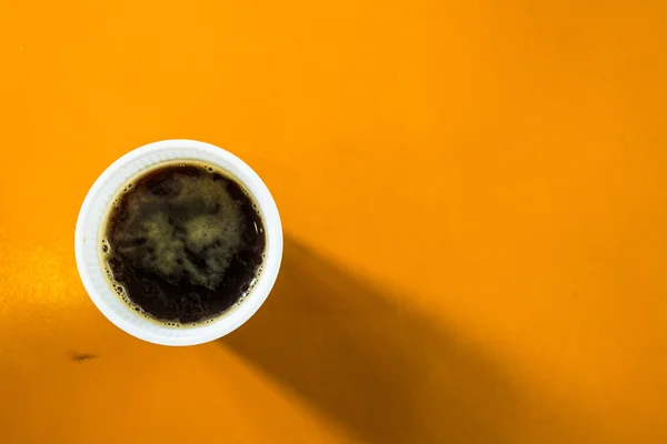Tasse schwarzen Kaffee auf orangefarbenem Hintergrund. — Stockfoto