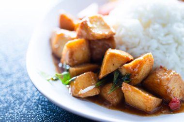 Tayland usulü kızarmış balık köftesi, fesleğenli ve biberli beyaz tabakta pilav ile servis ediliyor..