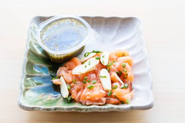 Baharatlı Tayland somon salatası, sarımsaklı, yeşil soğanlı ve seramik tabakta baharatlı deniz ürünleri soslu. Otantik Tayland füzyon çanağı.