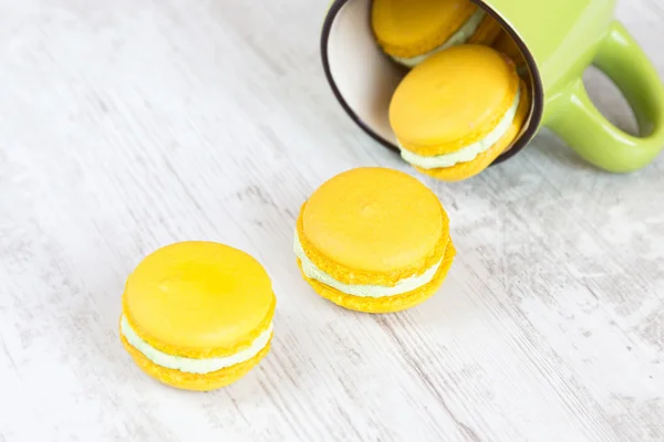 Yellow macaroons and green cup — Stock Photo, Image