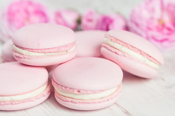 Macarrones rosados suaves con rosa sobre madera —  Fotos de Stock