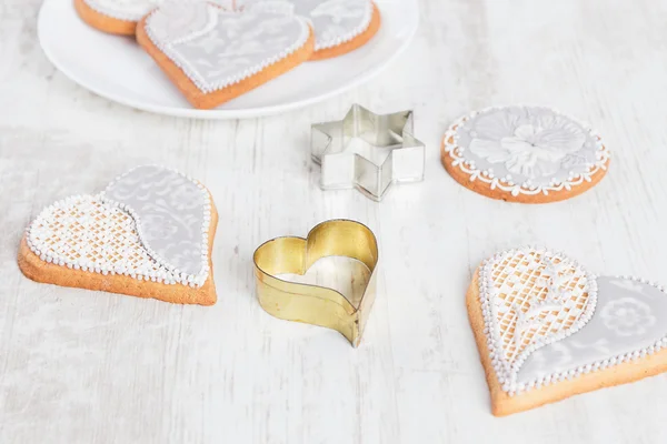 White gingerbread cookies in heart shape with cookie cutter — Stock Photo, Image