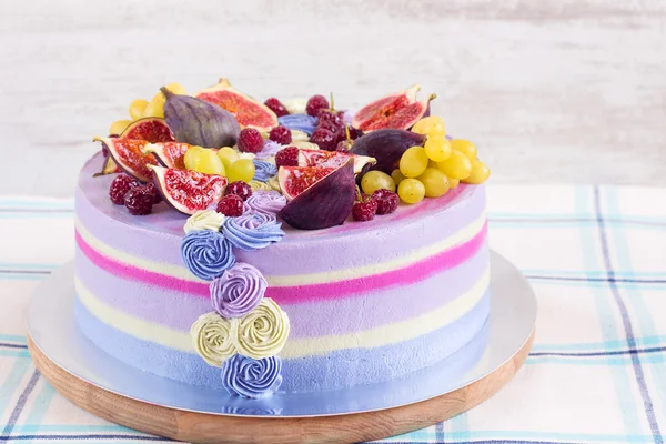 Gâteau violet et rose aux fruits sur fond de bois blanc — Photo