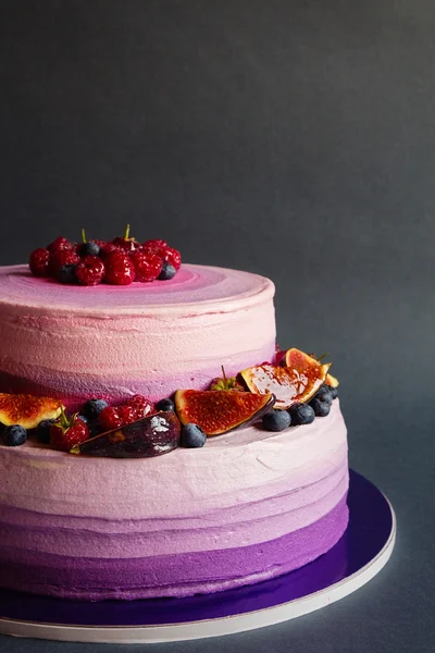 Два ярусных фиолетовых торта с фруктами на темно-сером фоне — стоковое фото