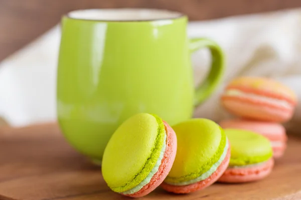 Groen en roze kleurrijke bitterkoekjes met groene mok — Stockfoto