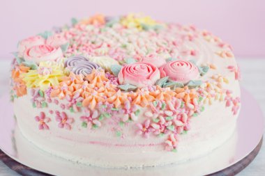 Pastel pembe kek krem çiçeklerle süslenmiş