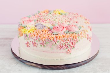 Pastel pembe kek krem çiçeklerle süslenmiş