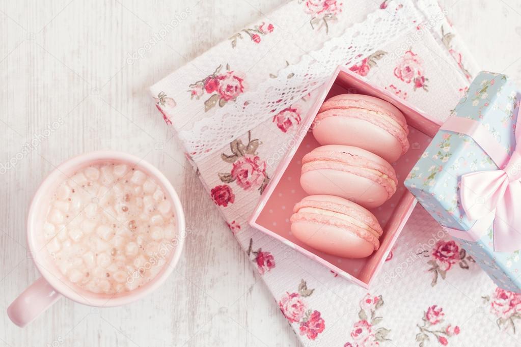 Pink macaroons in gift box with cup of coffee