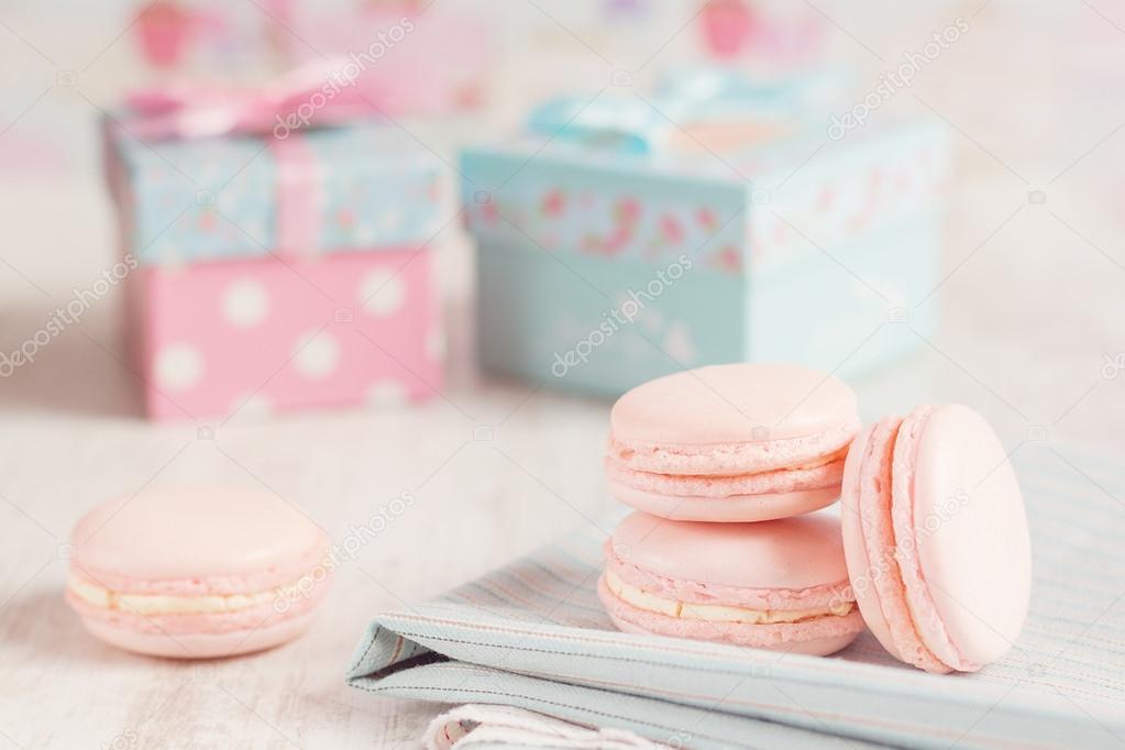 Pink macaroons with gift boxes on background