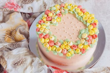Kremalı pasta küçük sarı ve pembe Gül ile dekore edilmiştir.