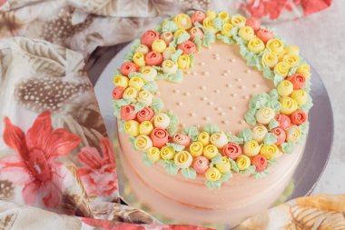 Kremalı pasta küçük sarı ve pembe Gül ile dekore edilmiştir.