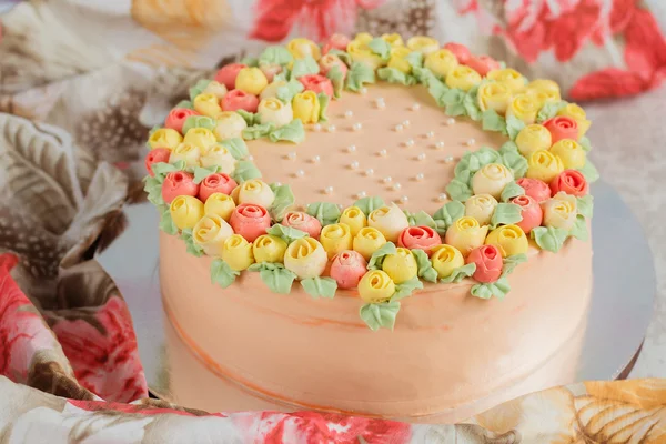 Kremalı pasta küçük sarı ve pembe Gül ile dekore edilmiştir.