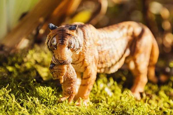 Tigress with cub in teeth. Tiger toy figurine in situation. — Stock Photo, Image