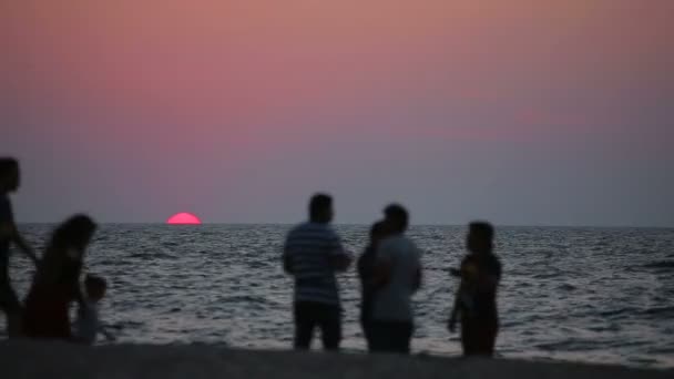 Ludzie odpoczynek na plaży o zachodzie słońca — Wideo stockowe