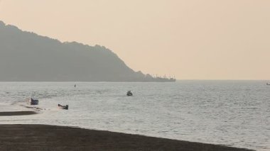 Tekneler ve balıkçılar siluetleri ile puslu tropikal deniz manzarası