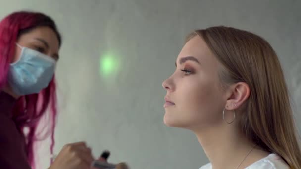 Artista de maquillaje usando máscara en el trabajo aplicando maquillaje de modelo — Vídeo de stock