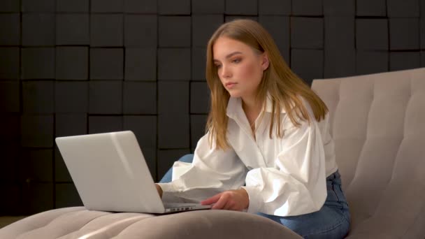 Jonge vrouw met behulp van laptop terwijl zitten op een stoel — Stockvideo