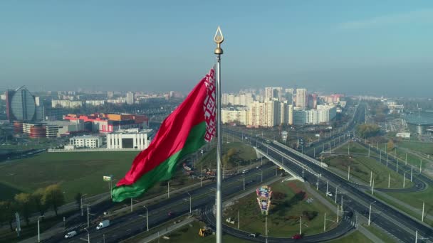 Bandera bielorrusa ondeando sobre el cielo azul y el paisaje urbano de Minsk en una mañana soleada — Vídeos de Stock