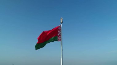 Güneşli bir sabahta mavi gökyüzünde dalgalanan Belarus bayrağı