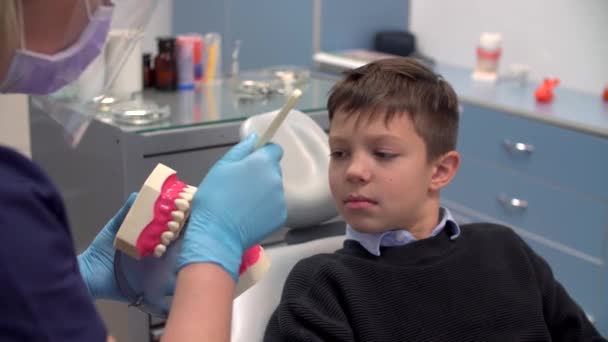 치과 의사는 소년에게 치아를 올바로 닦도록 가르친다 — 비디오
