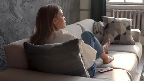 Mujer joven usando smartphone en un sofá — Vídeos de Stock