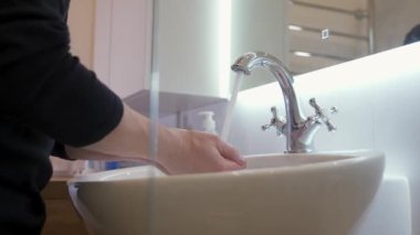 Genç adam tuvalette yüzünü yıkıyor. Hijyen kavramı