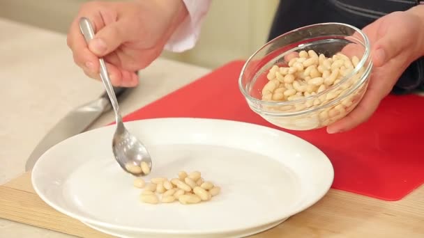 Kocken att sätta vita bönor på en tallrik för en sallad — Stockvideo