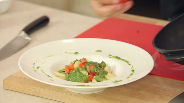 Kocken att sätta stekt röda körsbärstomater på Pasta med grön Pesto i en tallrik — Stockvideo