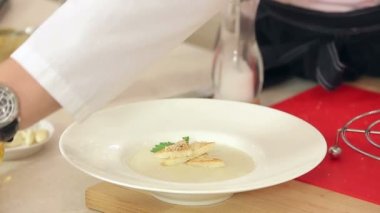 Şef koyarak dereotu, maydanoz, tuz ve biber krem çorbası, kızarmış tost ve rendelenmiş peynir ile bir tabak içinde olduğunu