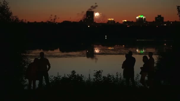 Семейные пары силуэты с праздничным городским пейзажем отражаются в воде на заднем плане — стоковое видео