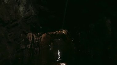 Yeraltı nehri olan karanlık bir mağaranın turistik cazibesini keşfediyorlar.