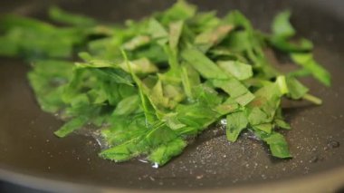 Kızartma tavasında taze ıspanak ve karamelli soğan.