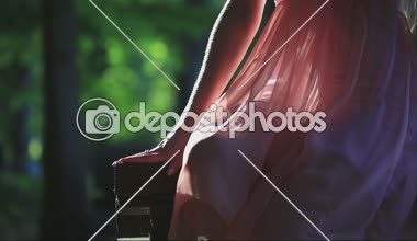 Güneşli bir yaz günü banktaoturuyor pembe elbiseli kız