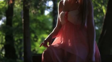 Güneşli bir yaz günü banktaoturuyor pembe elbiseli kız