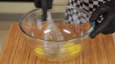 Şef omlet pişirirken cam bir kasede yumurta çırpıyor.