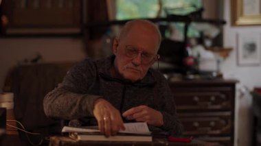 Kronik engelli yaşlı yetişkin tekerlekli sandalyede oturan masaüstü bilgisayarının evraklarıyla çalışıyor.